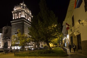 A historic building with a prominent tower, a paved walkway, and a flag. - Abittare Hotels (Cusco)