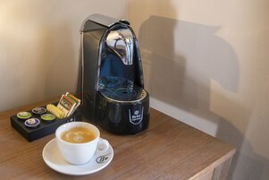 Een koffiezetapparaat, een kop koffie en een houder voor koffiekapsules op een houten tafel.