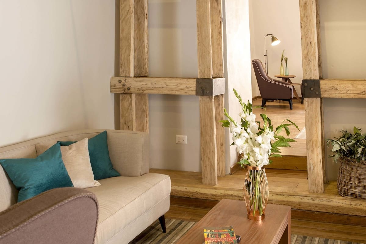 Una sala de estar con un sofá, una mesa de centro con un libro y un jarrón con flores.