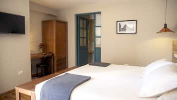 Un dormitorio con cama, escritorio, silla, armario, puerta y un cuadro colgado en la pared.