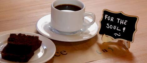 Una taza de café sobre un plato, una rebanada de pastel en un plato y un letrero que dice "For the Soul!"