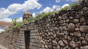 A stone wall with a small opening, leading to a building with a dome. - Abittare Hotels (Cusco)