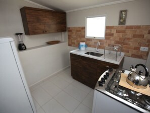 A kitchen with a gas stove, a sink, wooden cabinets, and a window.