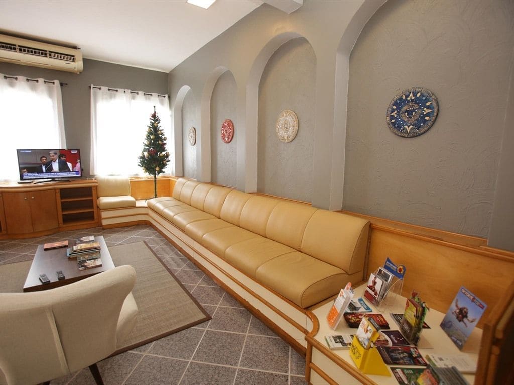 Un vestíbulo de hotel con un sofá de cuero, una mesa de centro, un televisor y un árbol de Navidad.