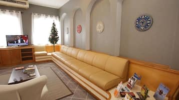 Um saguão de hotel com um sofá de couro, uma mesa de centro, uma TV e um pinheiro de Natal.