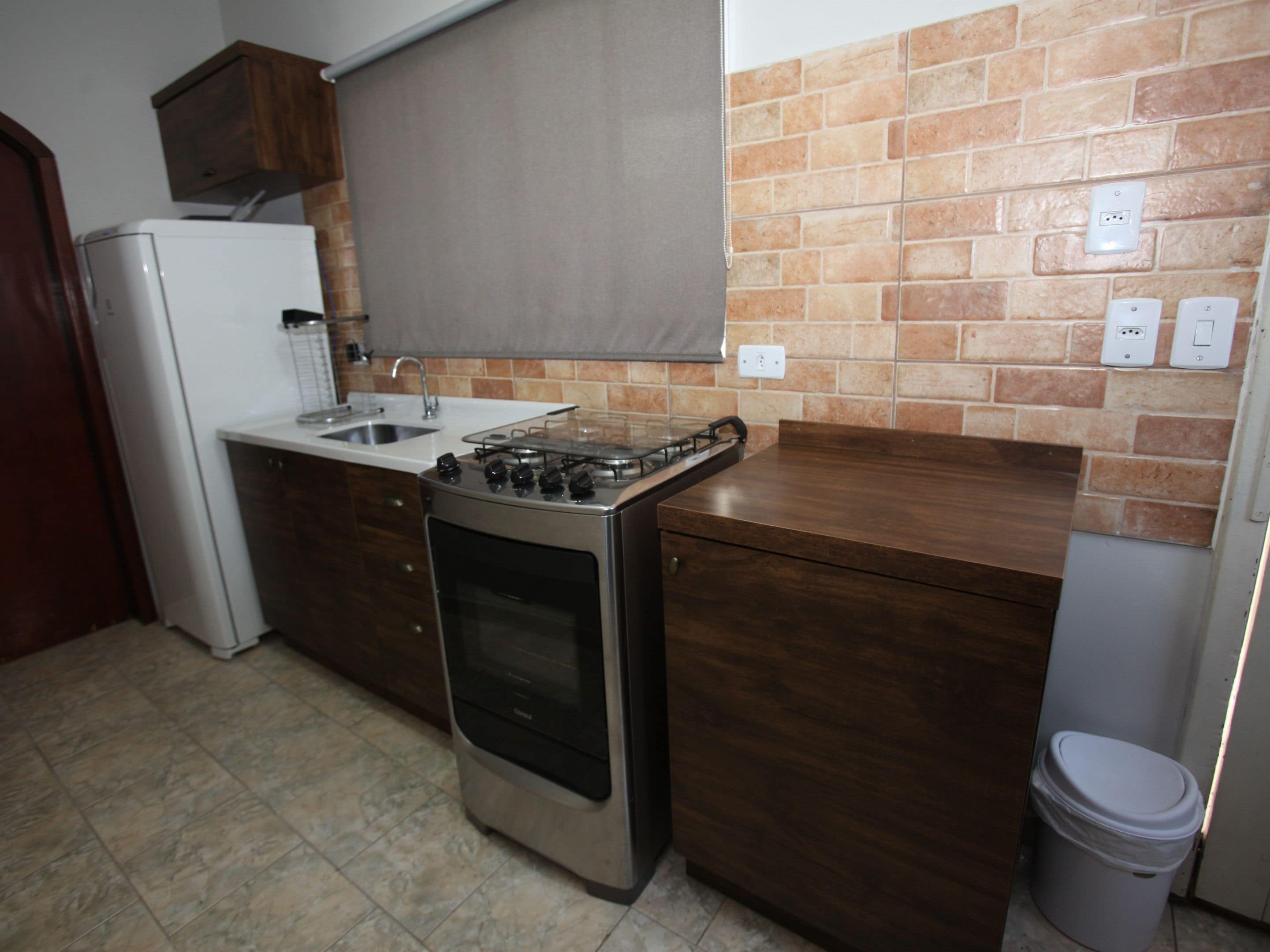 Cozinha compacta com fogão a gás, forno e pia.