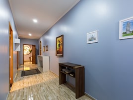 Un pasillo con piso de madera, una consola blanca y obras enmarcadas en las paredes.