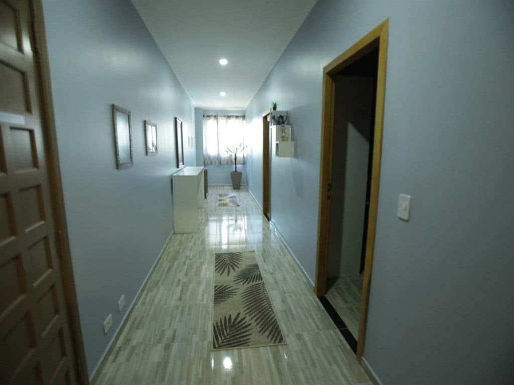 A hallway with a patterned floor, a door on the left, and a light fixture on the ceiling.