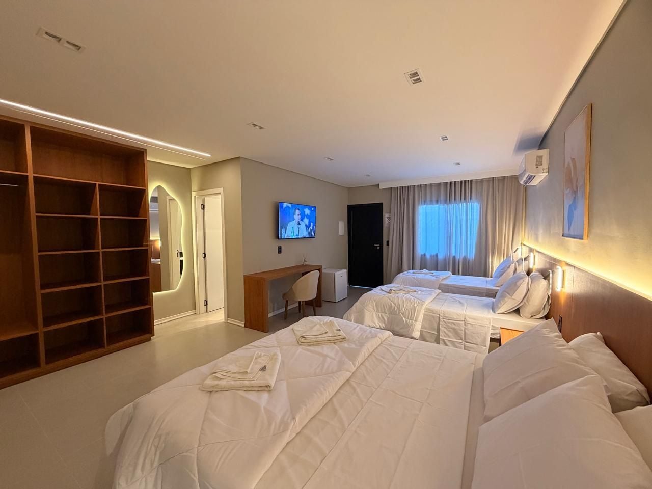 A hotel room with two beds, a TV, a desk, and a wardrobe.