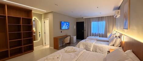 A hotel room with two beds, a TV, a desk, and a wardrobe.
