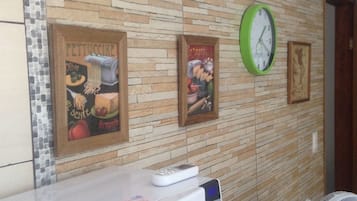 A wall with framed advertisements, a clock, and a microwave on a counter.