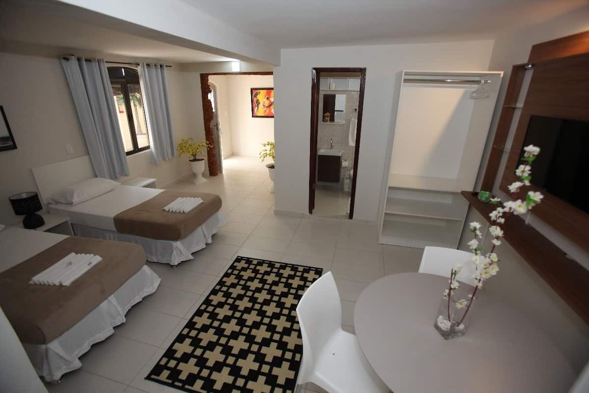 A hotel room with two beds, a small sitting area, a bathroom, and a TV.