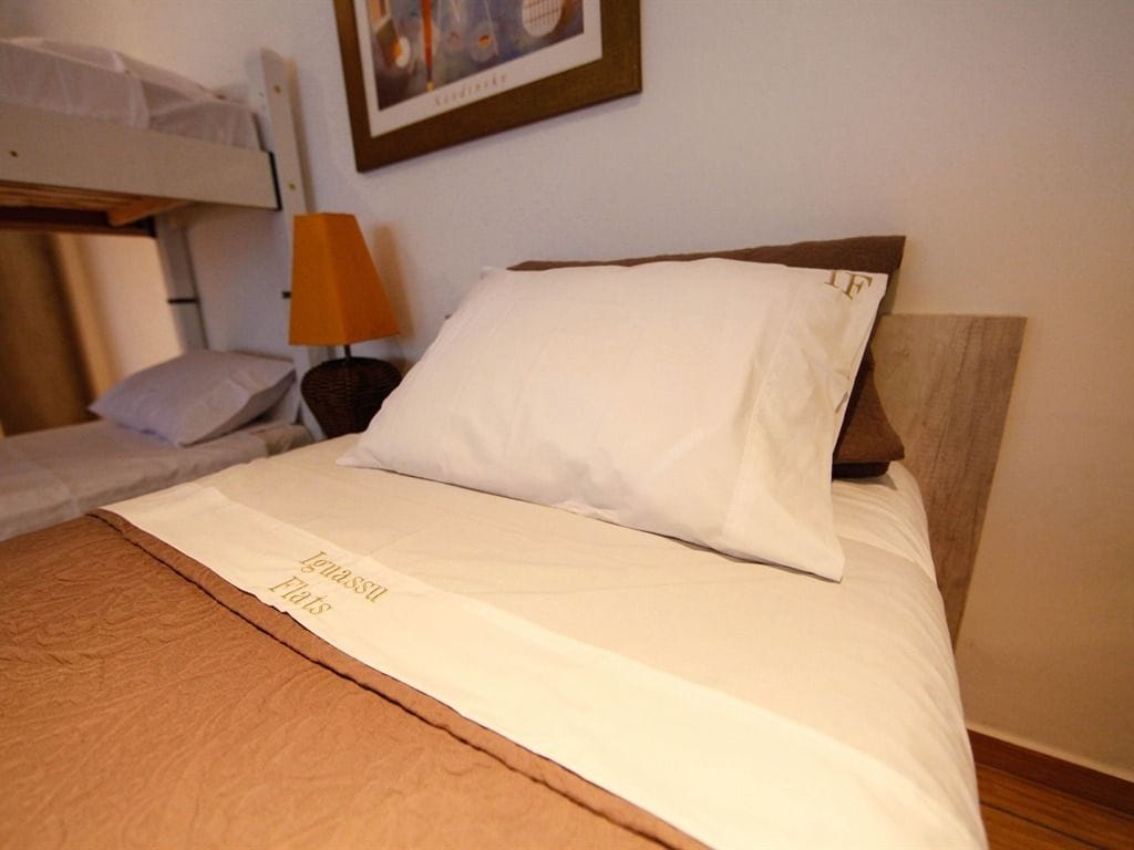 Ein Etagenbett mit einem weißen Kopfkissen und einem Holz-Kopfteil.