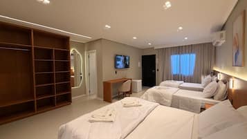 A hotel room with two beds, a desk, a TV, and a wardrobe.