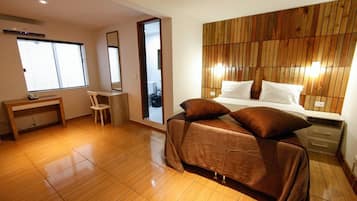 Quarto com cama, mesa de cabeceira, cadeira e cabeceira de madeira.