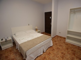 Un dormitorio con cama, mesita de noche, lámpara, armario y puerta de baño.