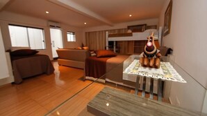 Une chambre d’hôtel moderne, équipée d’un lit, d’un canapé, d’une table à manger agrémentée d’un objet décoratif, et offrant une vue sur l’extérieur.
