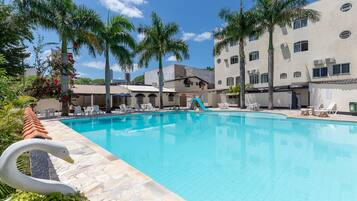 Una piscina al aire libre, sombrillas, sillones reclinables de piscina