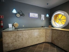 A reception desk with a globe, a bicycle, and a clock on the wall. - Iguassu Flats Hotel (Foz do Iguaçu)