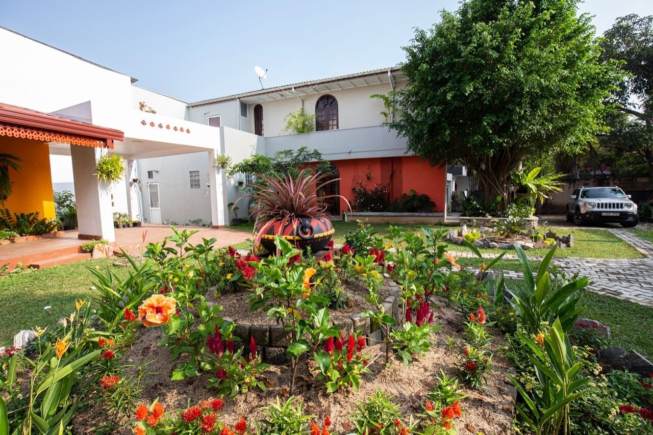 A courtyard with a garden, a white building with a red roof, and a parked car.