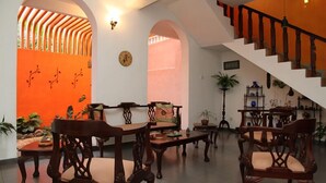 A spacious living area with wooden furniture, a staircase, and a bright orange accent wall. - Breeze of Paradise (Nugegoda)