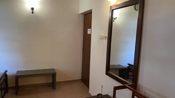 A hallway with a wooden bench, a small table with a bowl, a mirror, and a light fixture on the wall.