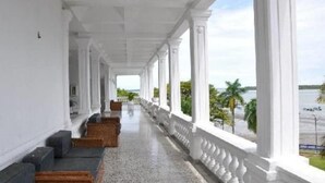 Un corredor cubierto con columnas blancas y vistas al mar.