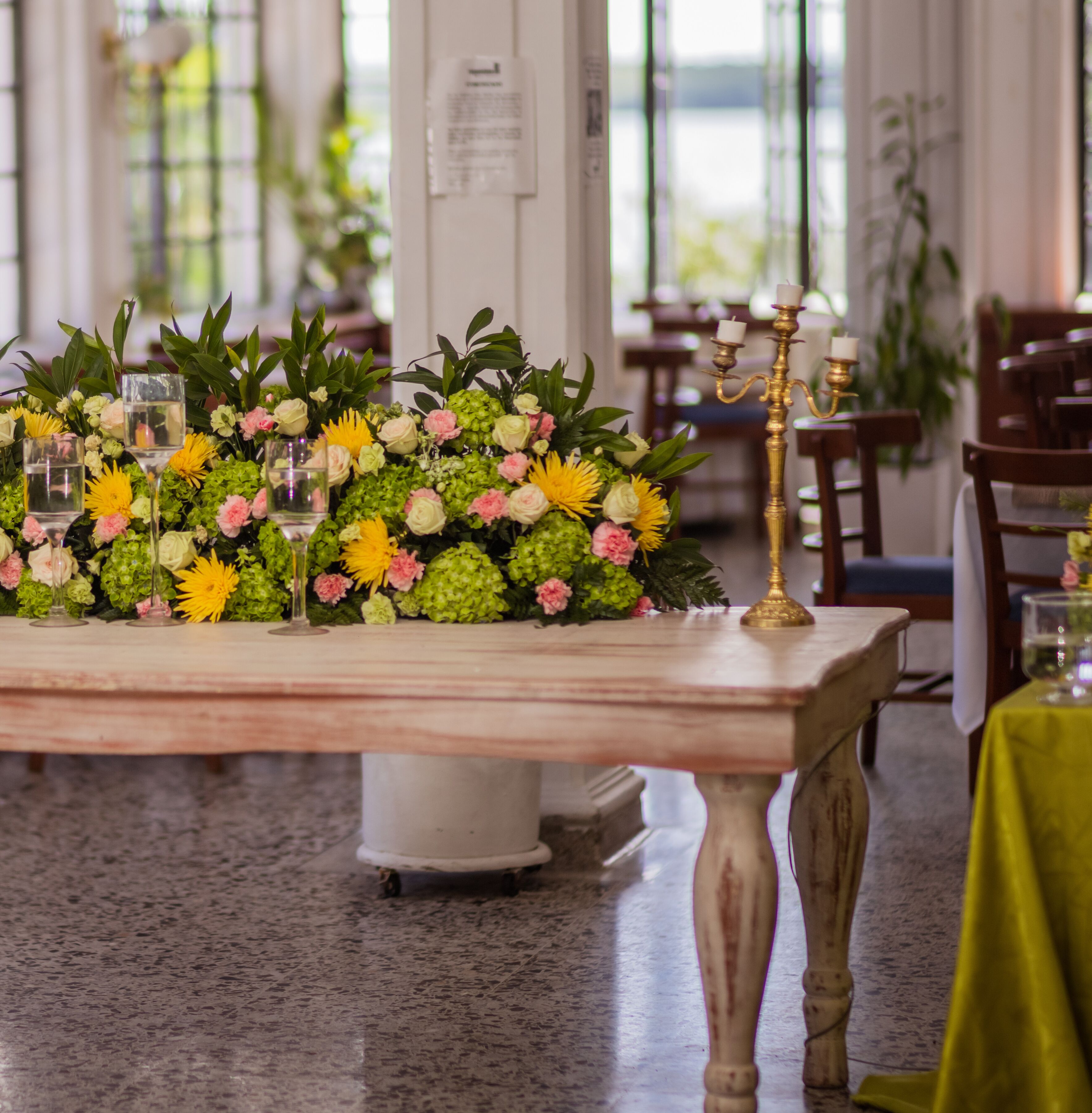 Una mesa con un centro de mesa floral, un candelabro y vasos de agua.
