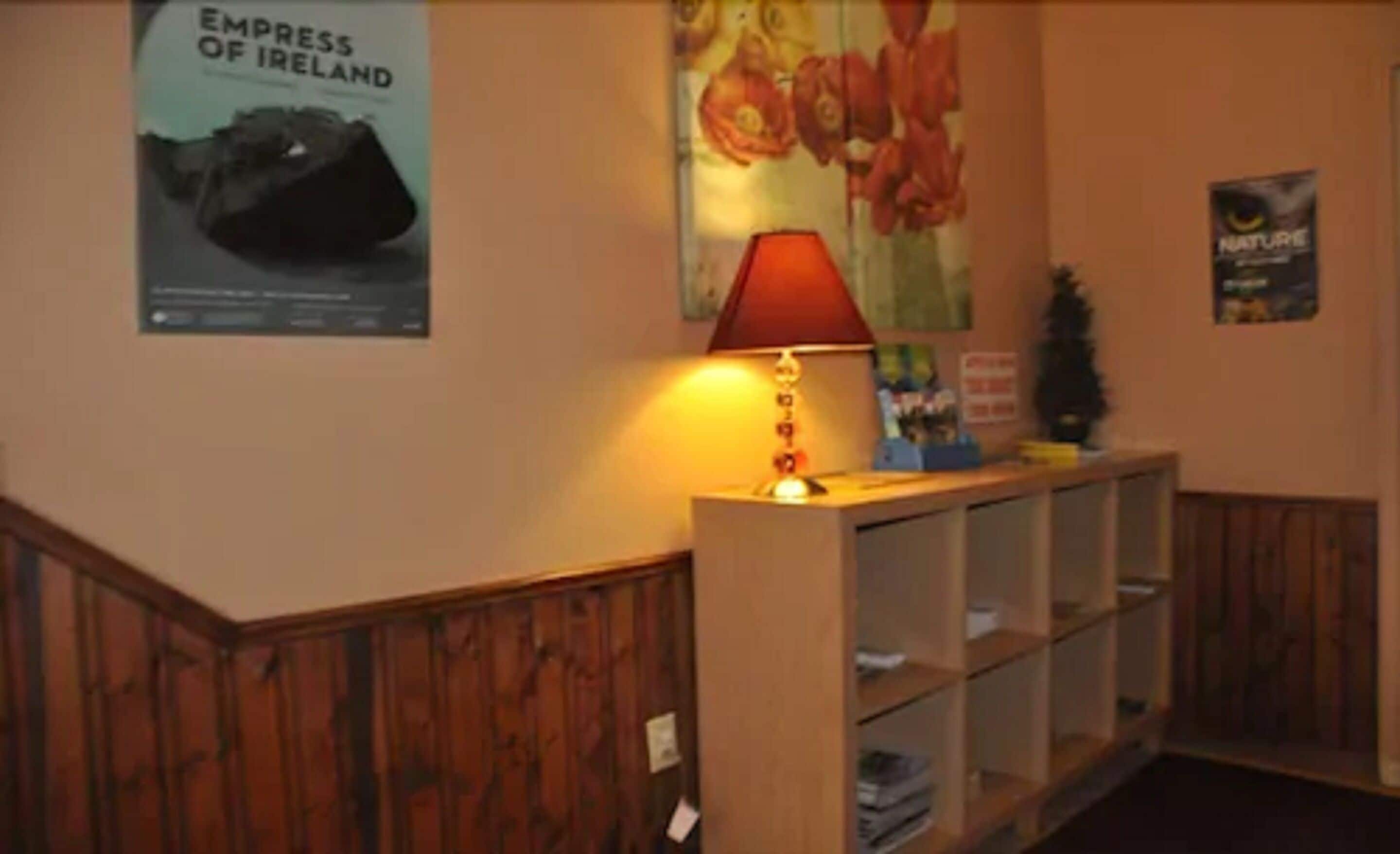 Un'area reception con una scrivania in legno, una lampada rossa e un poster raffigurante una nave.
