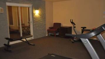 A room with a treadmill, a chair, and a desk.