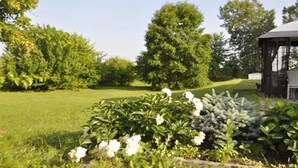 Un jardín con un pabellón, abundante vegetación y plantas en flor.
