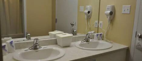 A bathroom with two sinks, a mirror, and a towel dispenser.
