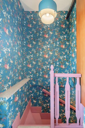 A room with floral wallpaper, a wooden staircase, and a ceiling light fixture. - España (Rome)