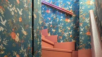 Eine Treppe mit floraler Tapete im Hintergrund und einem runden Spiegel oben.