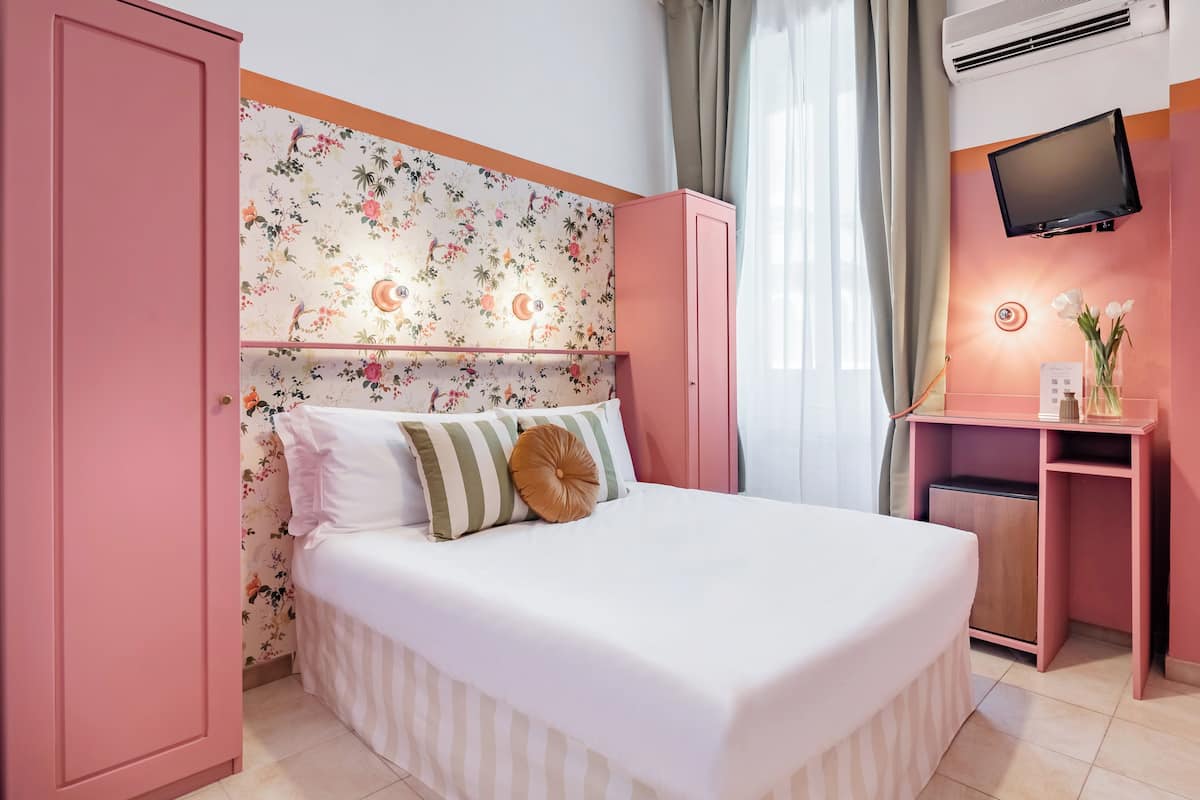 A bedroom with a bed, a dresser, a TV, and a desk.