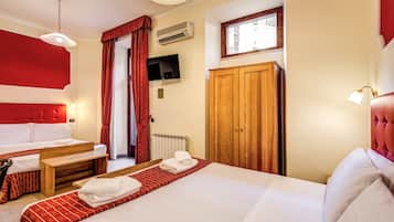 Ein Hotelzimmer mit einem großen Bett, einem kleineren Bett, einem Holzschrank, einem Fernseher und einem Fenster mit Blick.