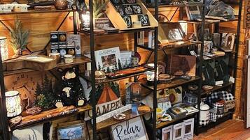 A rustic cabin interior with wooden walls and shelves displaying camping gear, mugs, and decorative items.