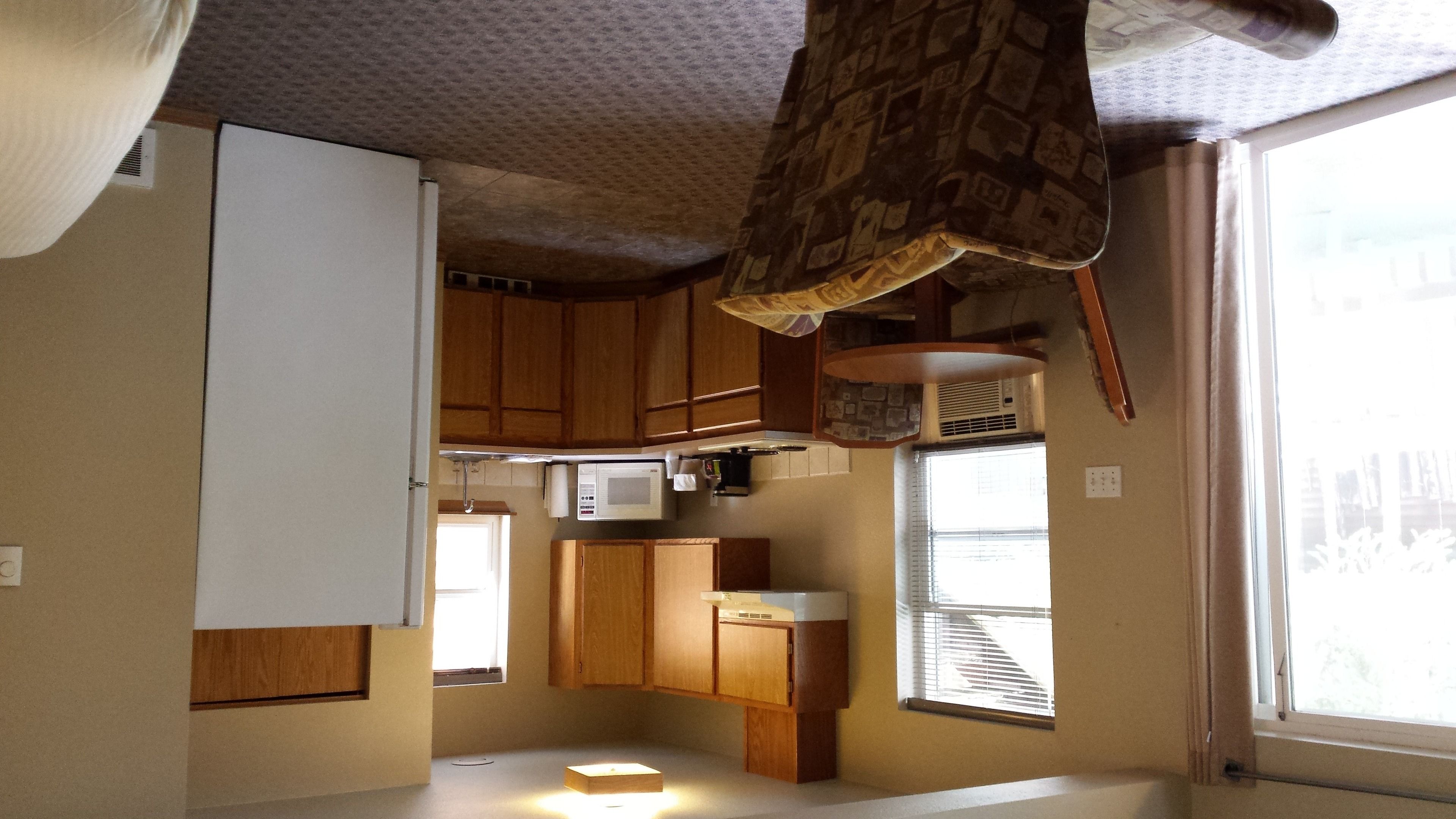 A compact kitchen with wooden cabinets, a microwave, and a small refrigerator.