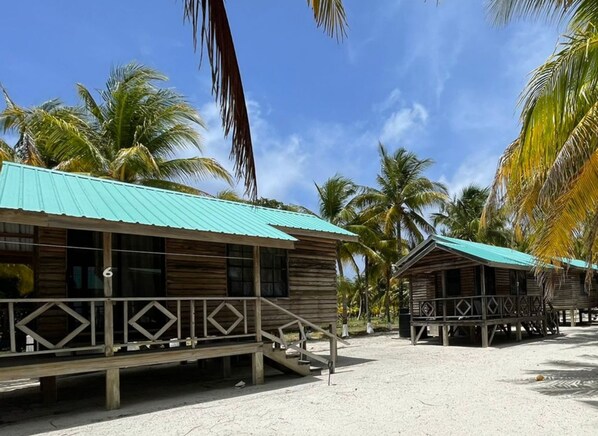 A beachfront resort with wooden cabins, each featuring a balcony and a metal roof. - Isla Marisol Resort (Glover's Reef)