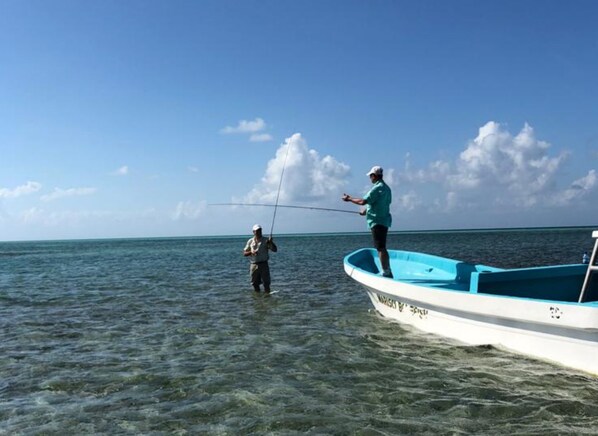 Two people fishing in a boat on a calm sea. - Isla Marisol Resort (Glover's Reef)