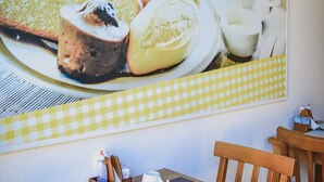 A dining area with a table set for breakfast, including plates of food and a coffee cup. - Pousada Beach House (Cabo Frio)