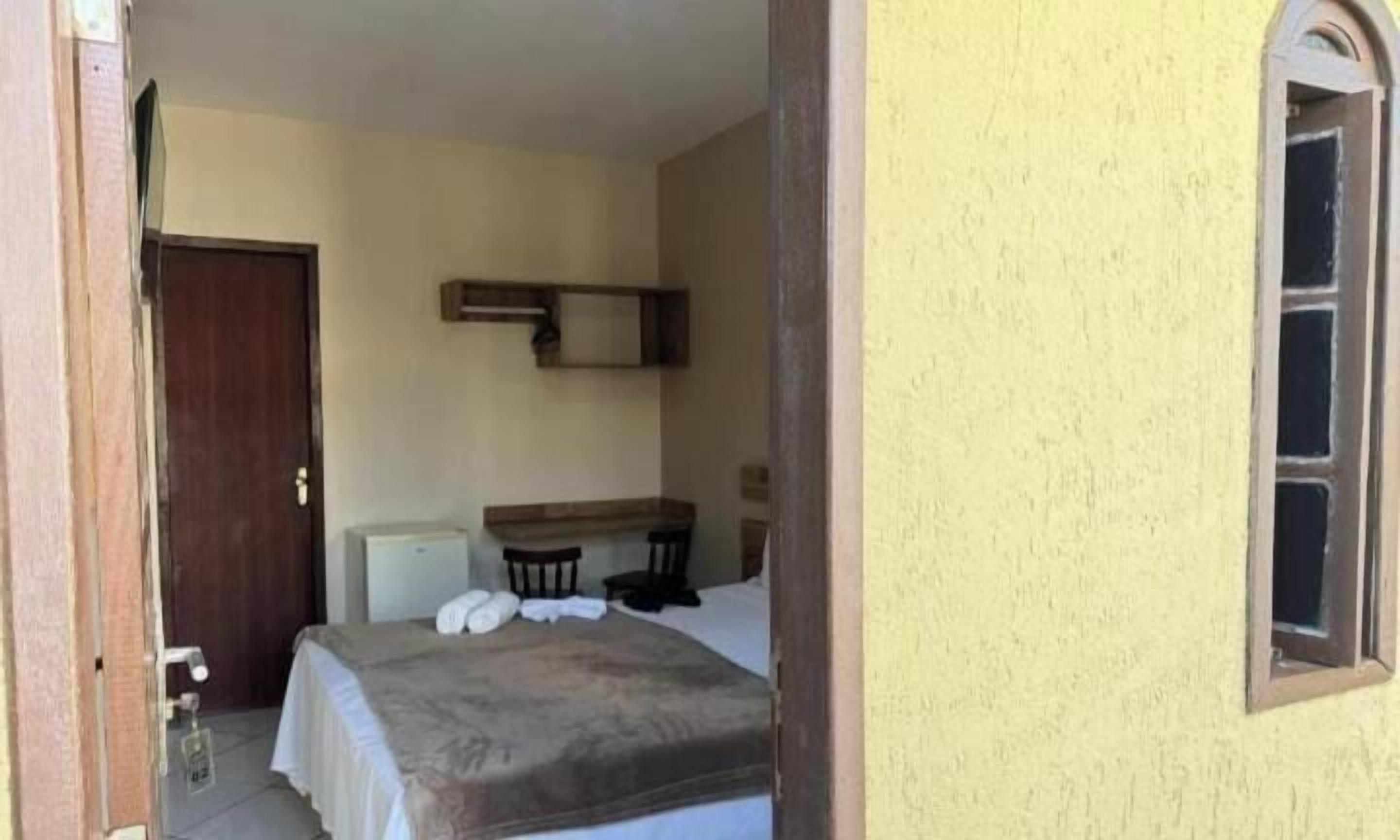 A bedroom with a bed, a desk, and a chair.