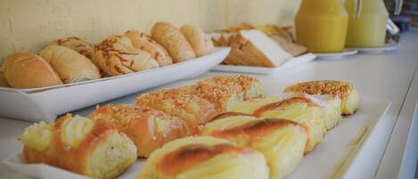A breakfast buffet with various pastries and a pitcher of orange juice.