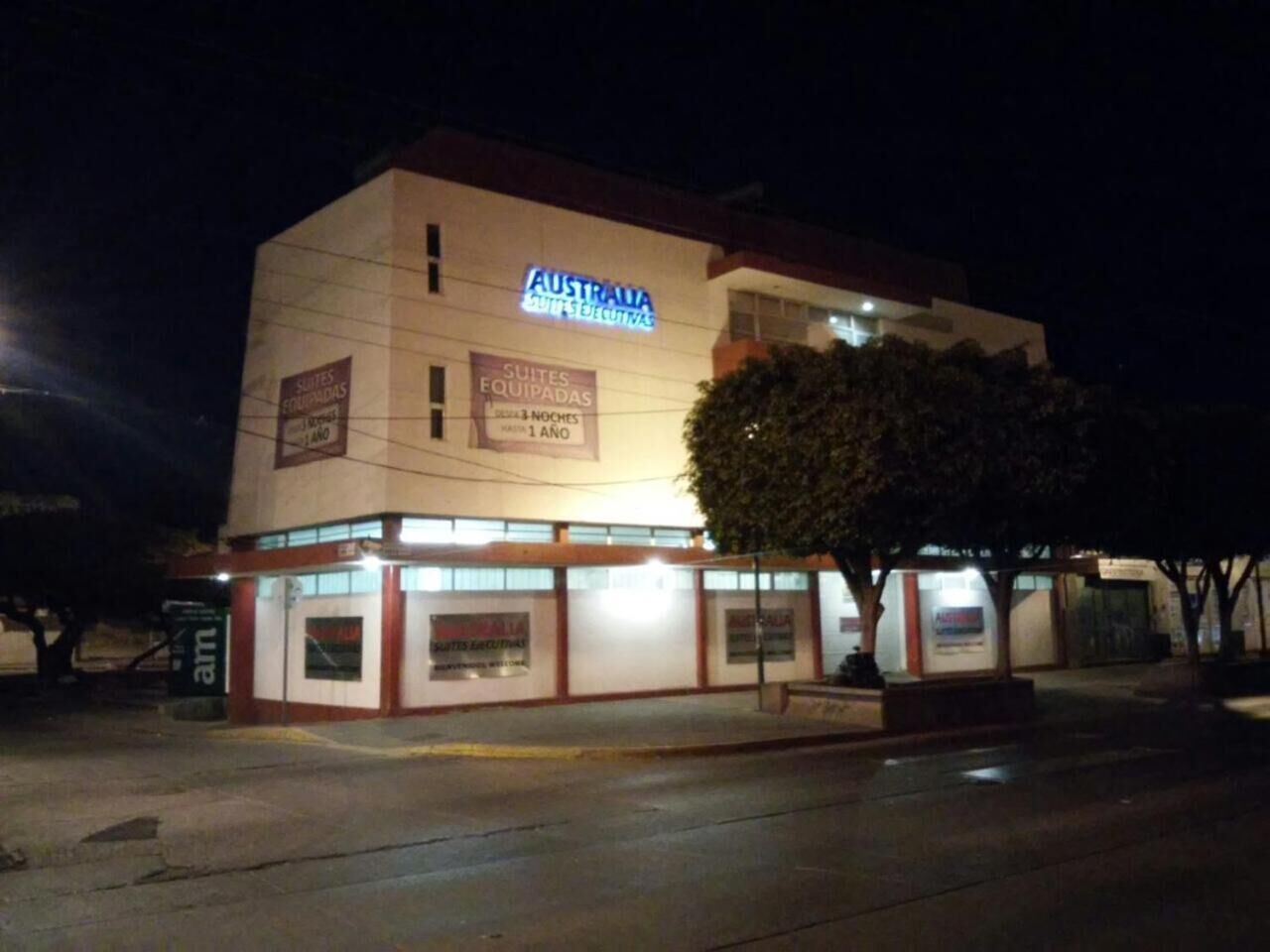 A hotel named "Australia Suites & Executive" with signage indicating "Suites Equipadas" and "1 Ano."
