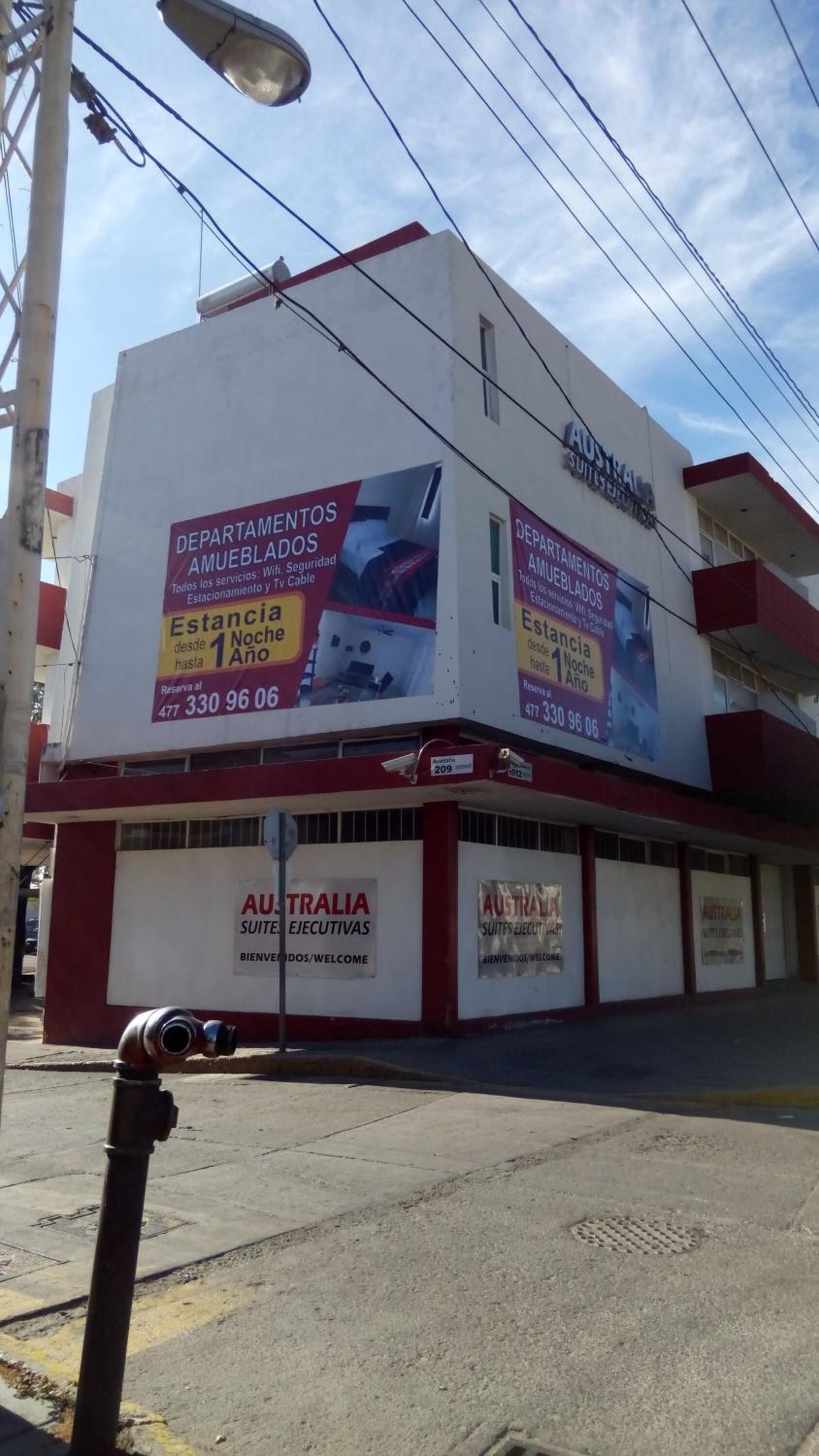 A building with signage for 'Australia Suites Ejecutivas' and 'Estancia desde 1 Noche hasta 1 Año'.