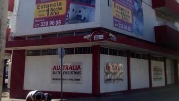 A building with signage for 'Australia Suites Ejecutivas' and 'Estancia desde 1 Noche hasta 1 Año'.