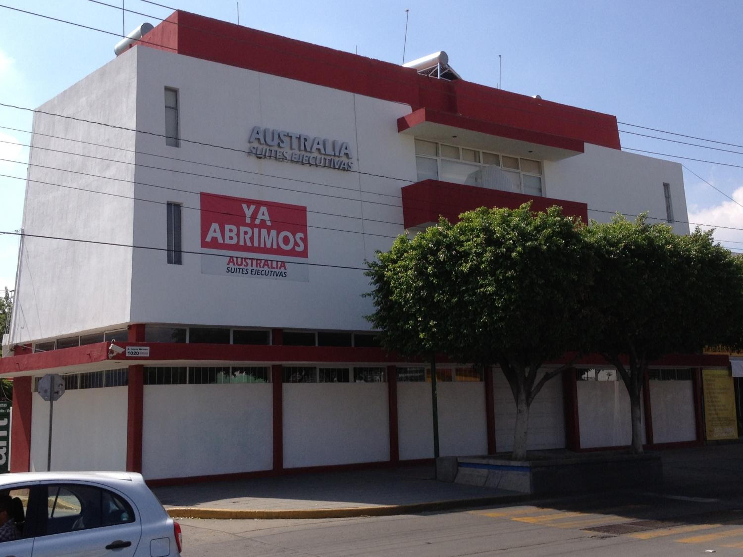 A building with signage for 'Australia Suites Ejecutivas' and 'YA ABRIMOS'.