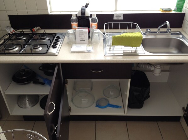 Una cocina con estufa a gas, pileta y diferentes utensilios de cocina.