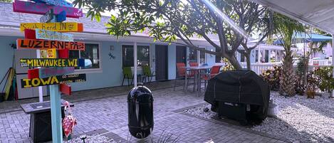 Un espace patio équipé d’un barbecue, de sièges d’extérieur et d’un panneau indicateur portant divers noms de destinations.