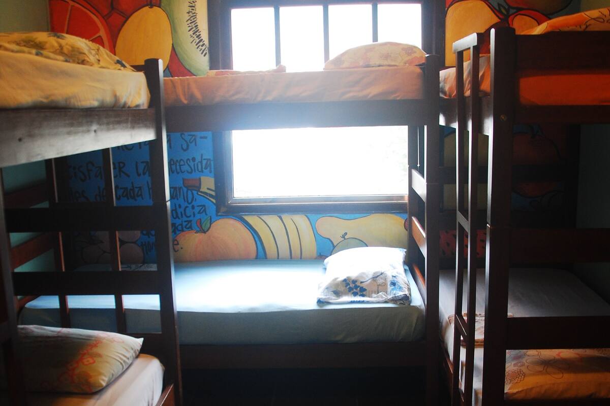 A bunk bed room with a mural of fruits on the wall.